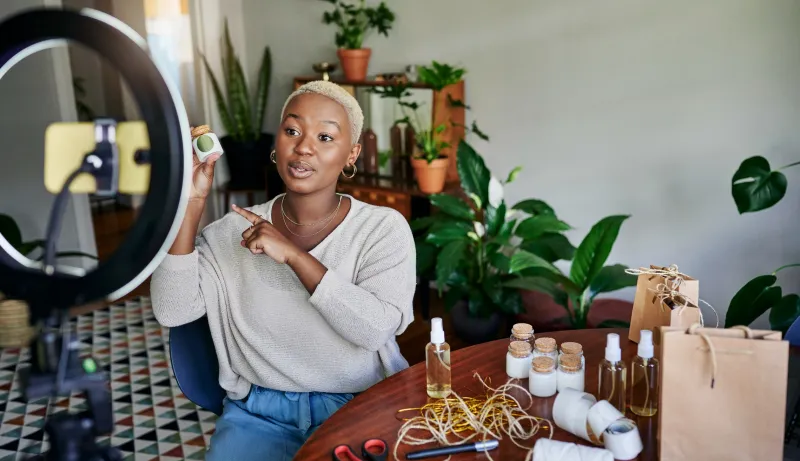 Influencer talking about a cosmetic product while doing an online vlogcast at home